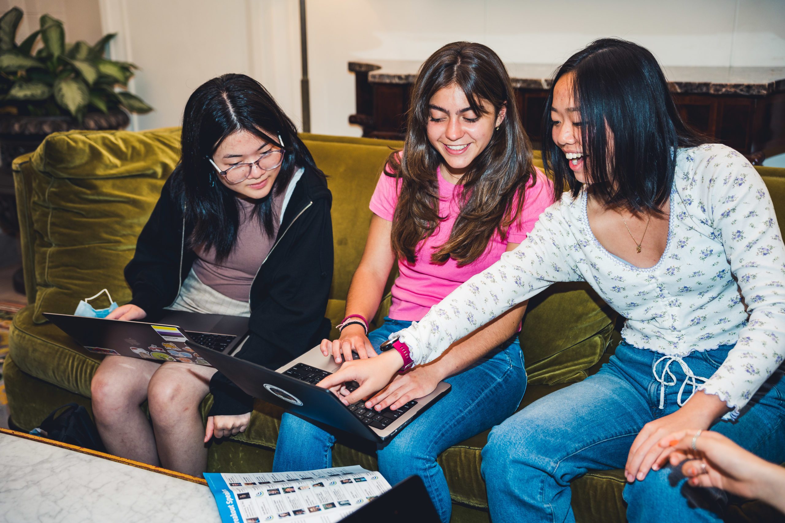 Three girls sitting on a couch looking at a computer